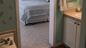 A bedroom with a bed, a bathroom with a sink and mirror, and a hallway with a door. - Country setting. Two miles from downtown Petoskey.  (Petoskey)