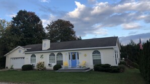 A single-story house with a blue front door, a chimney, and a garage. - Country setting. Two miles from downtown Petoskey.  (Petoskey)