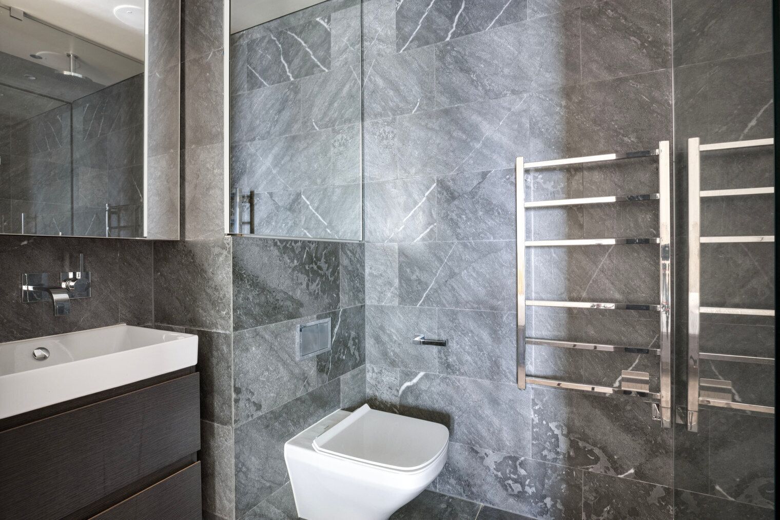 A modern bathroom with a white sink, a mirror, and a towel rack.
