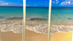 A beach with clear turquoise water and a sandy shore. - Stunning views of Seven Mile Beach, luxurious rooftop and oceanfront pool. (West Bay)