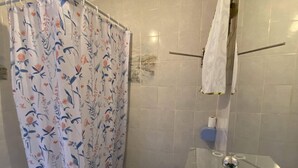 Une salle de bain avec un rideau de douche, des toilettes et une baignoire.