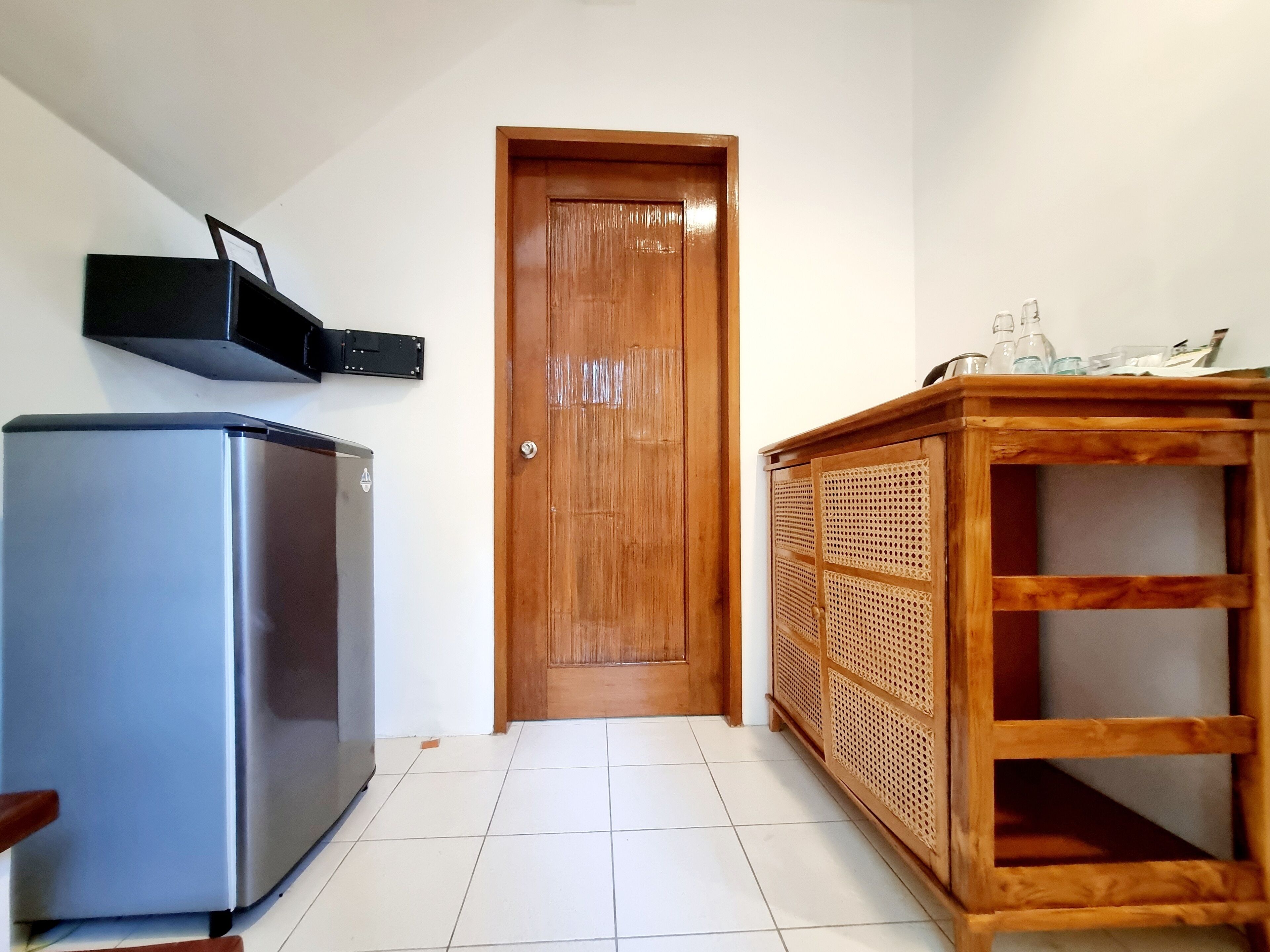Una cocina con un refrigerador, una puerta de madera y un armario de madera con estantes.