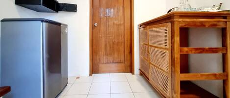 Una cocina con un refrigerador, una puerta de madera y un armario de madera con estantes.
