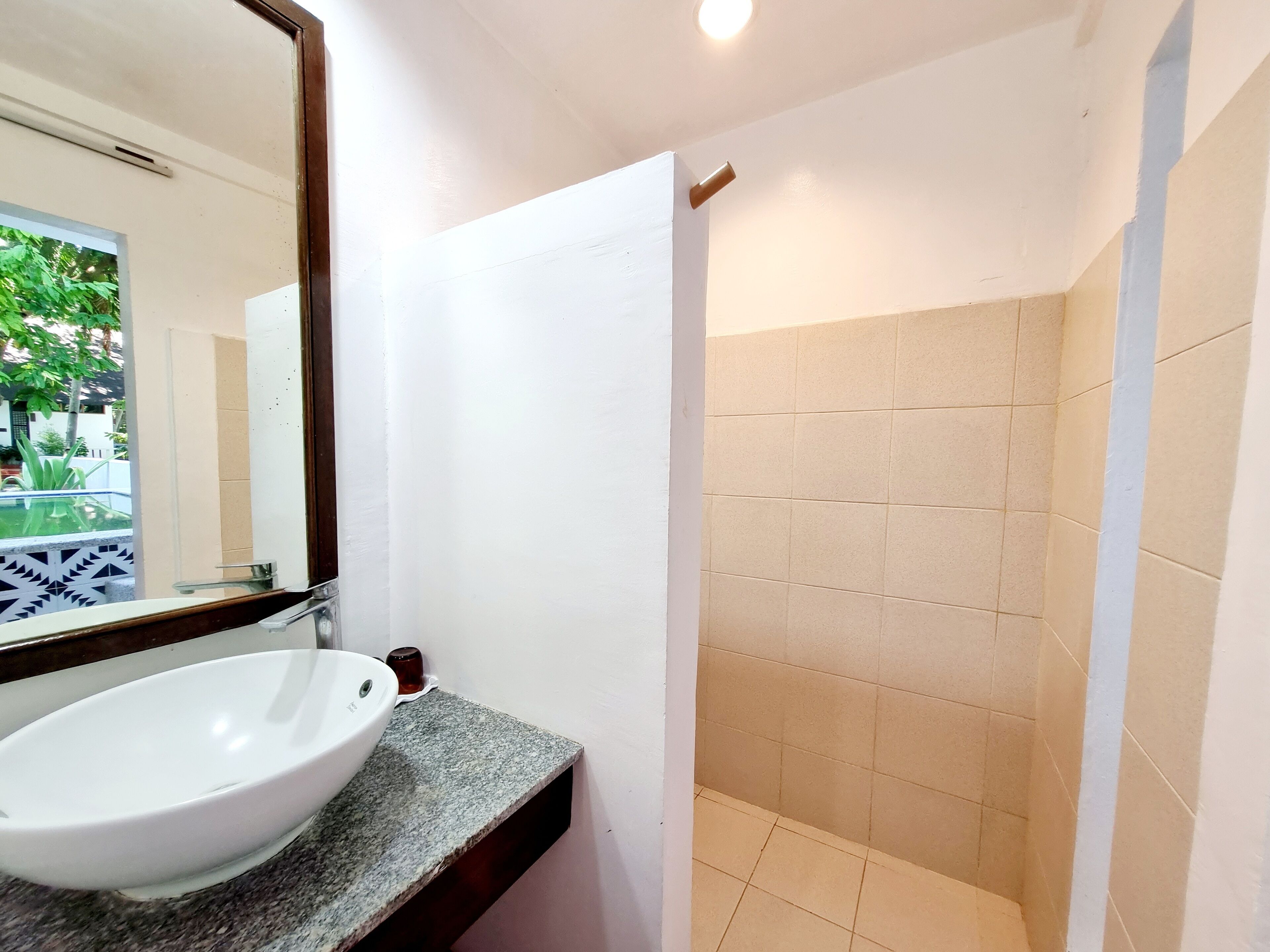 A bathroom with a white sink, a mirror, and beige tiled walls.
