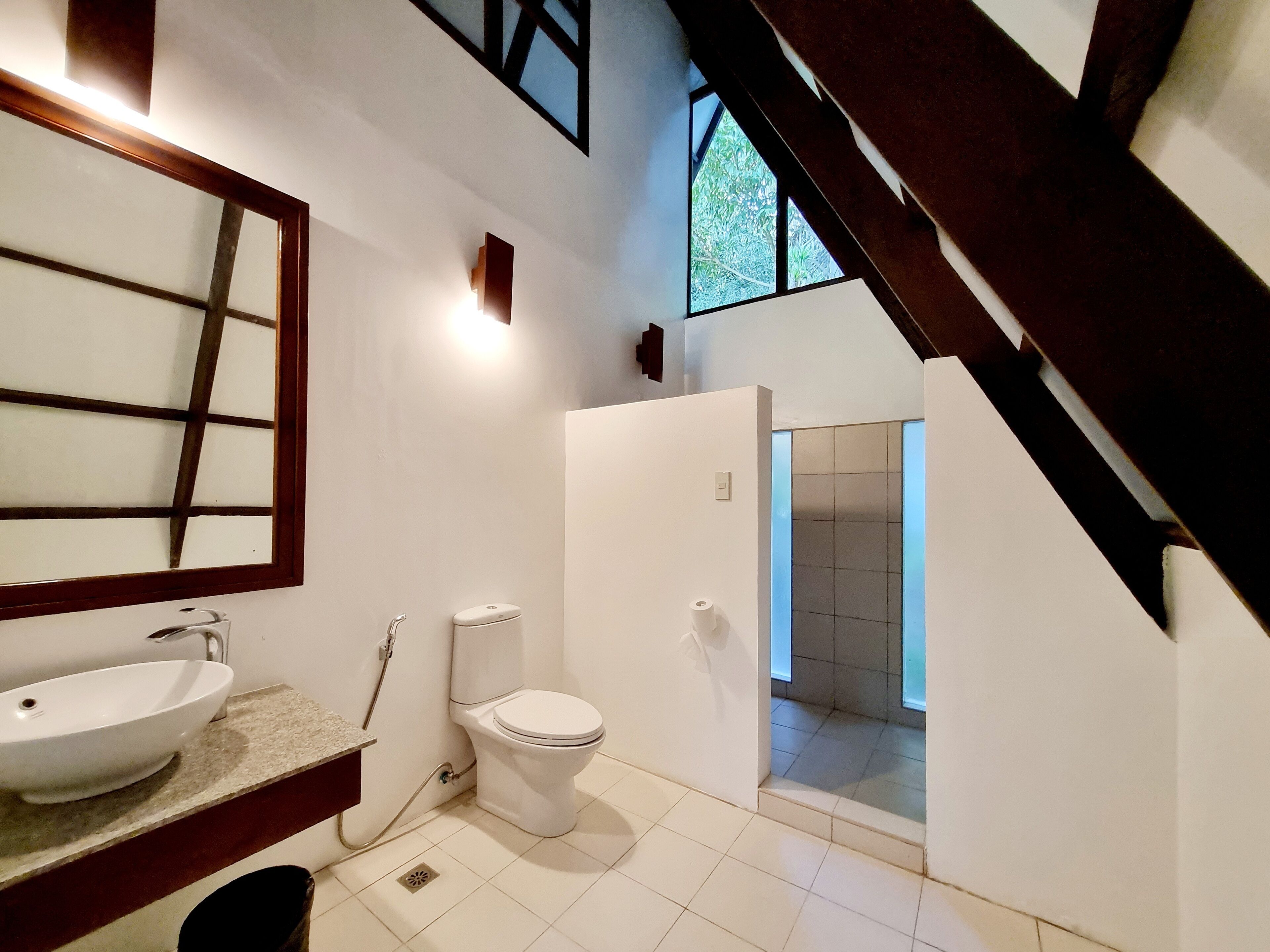 A modern bathroom with a large mirror, a sink, a toilet, and a shower area.