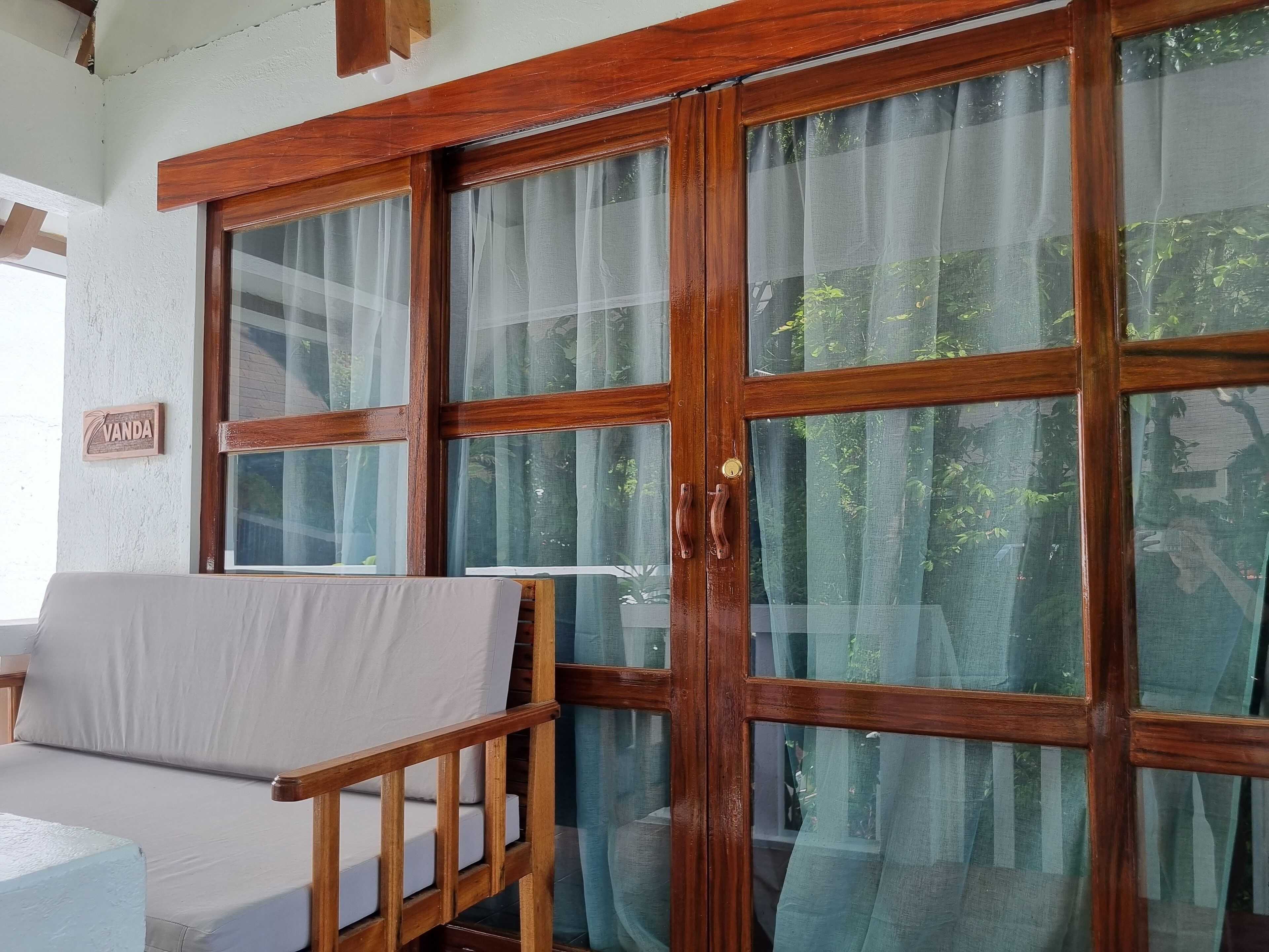 A room with a wooden-framed window, a sofa, and a sign reading "VANDA".