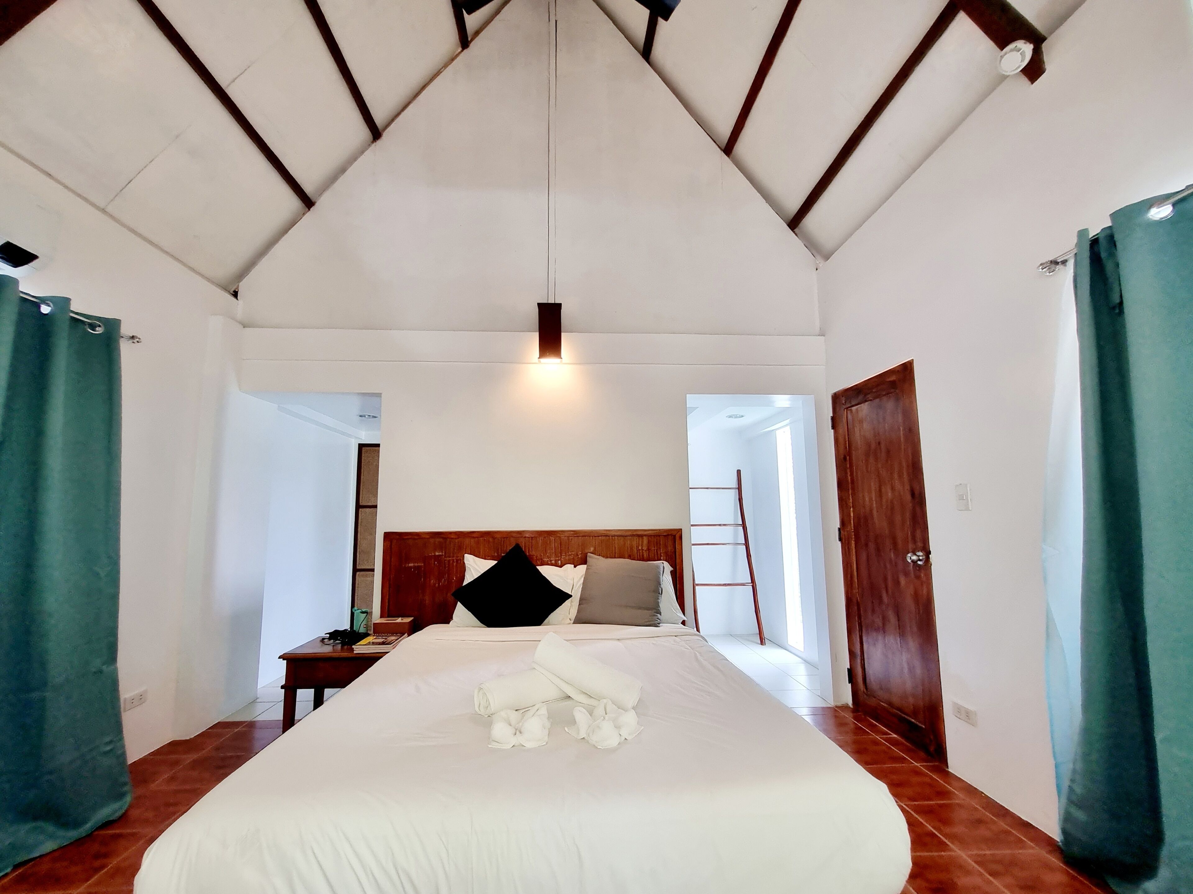 Een ruime slaapkamer met een groot bed, houten hoofdbord en een plafondventilator.