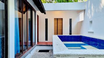 Un espacio exterior moderno con piscina, una puerta y un ventanal con cortinas.