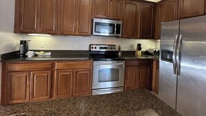 Una cocina con armarios de madera, un refrigerador de acero inoxidable, un microondas y un horno.
