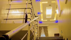 Eine Treppe mit Metallgeländer, einer Kristallleuchter und blauer Beleuchtung an den Wänden.