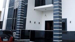 Ein modernes, zweistöckiges Haus mit Balkon und Garage, ein Auto fährt davor.