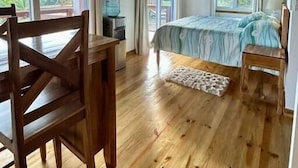 A bedroom with a bed, wooden furniture, and large windows.