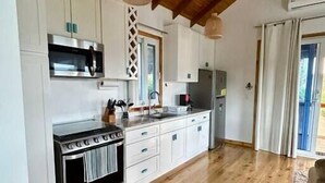 A modern kitchen with white cabinets, a stainless steel stove, and a wooden ceiling.