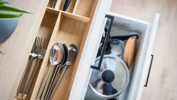 A drawer with utensils and a pot.