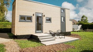 Een modern, gelijkvloers huis met een voordeur, twee ramen en een klein terras met buitenmeubels.