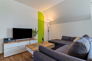 Un salon moderne avec un téléviseur à écran plat, une table basse, un canapé et une lampe sur pied.