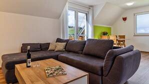 A modern living room with a sectional sofa, a wooden coffee table, and a bottle of wine. - Apartment "Lieselotte, 72 sqm" with Balcony and Wi-Fi (Oberkirch)