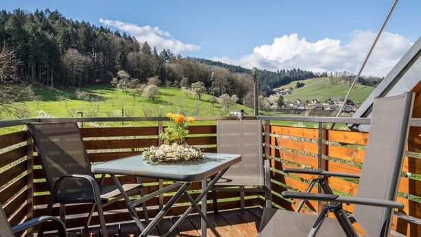 A balcony with a table and chairs, overlooking a green landscape and a village. - Apartment 'Rosalinde, 72 sqm' with Balcony and Wi-Fi (Oberkirch)