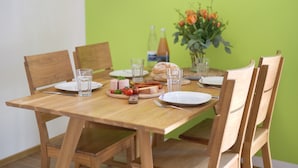 A wooden dining table set with plates, glasses, a loaf of bread, and a small fruit platter. - Apartment 'Rosalinde, 72 sqm' with Balcony and Wi-Fi (Oberkirch)