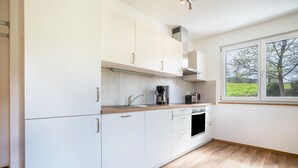 A modern kitchen with white cabinets, a wooden countertop, a built-in oven, and a window with a view of greenery. - Apartment 'Rosalinde, 72 sqm' with Balcony and Wi-Fi (Oberkirch)