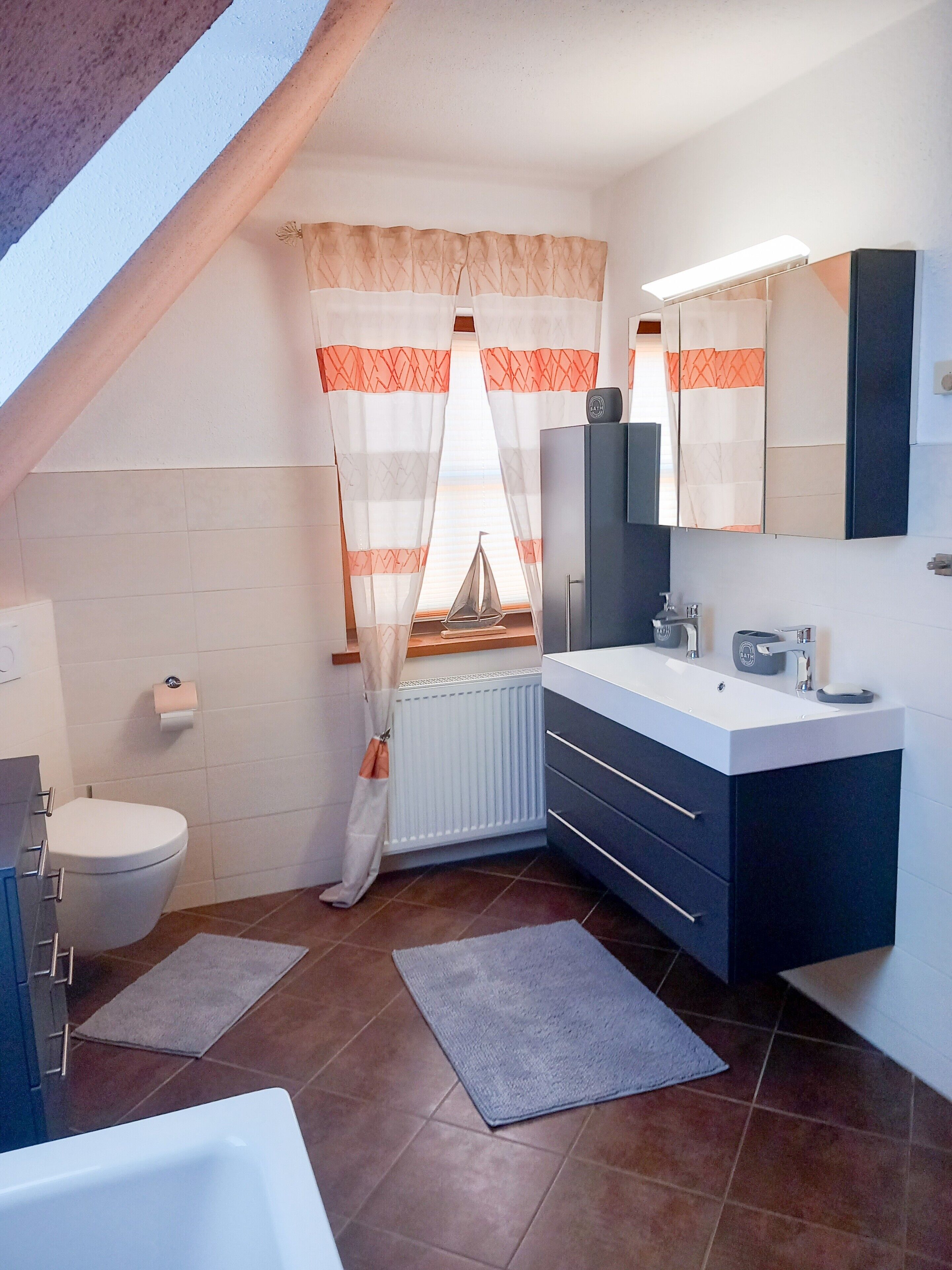 Un baño moderno con inodoro, lavamanos y zona de ducha.