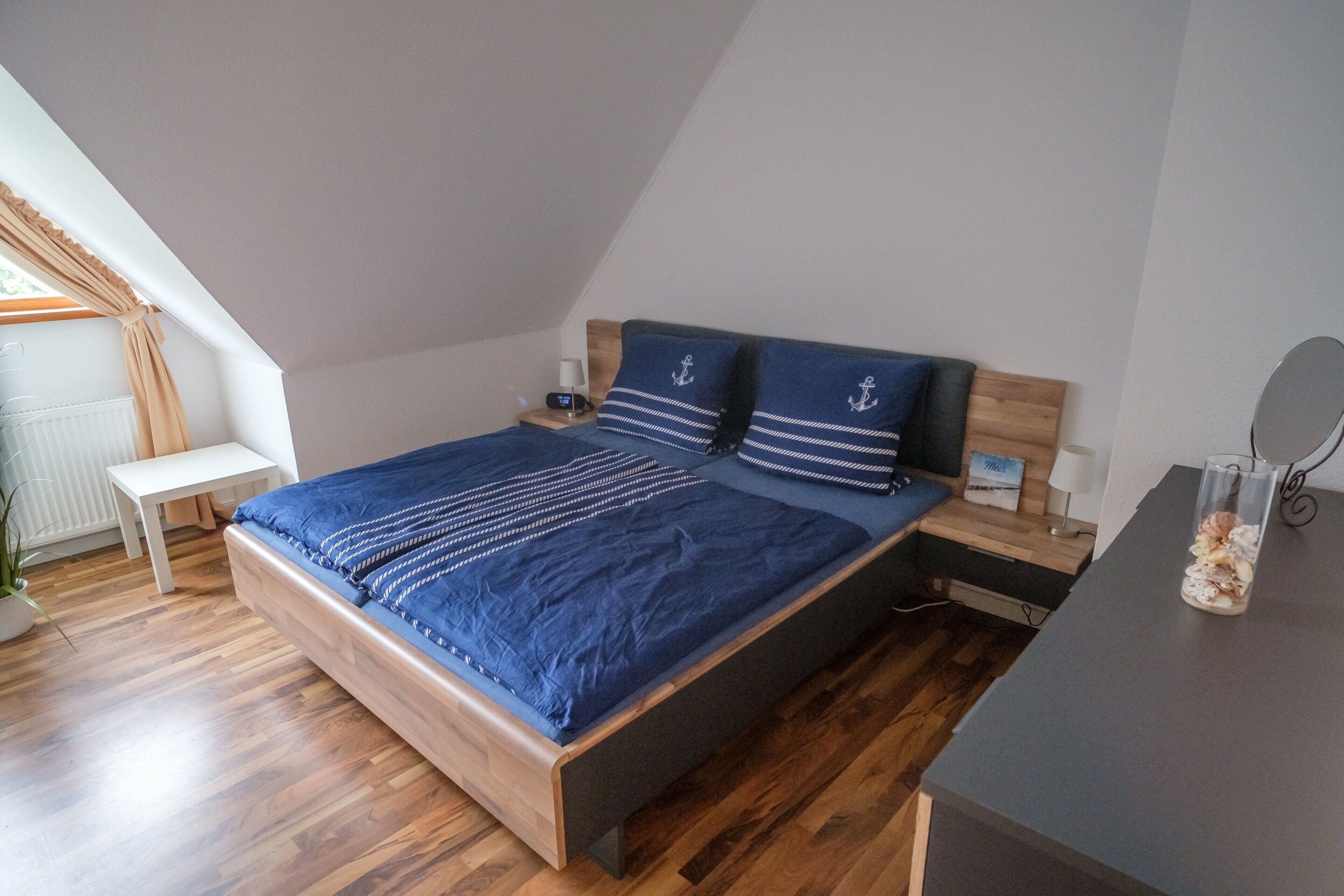 A bedroom with a bed, bedside table, lamp, and a small mirror.