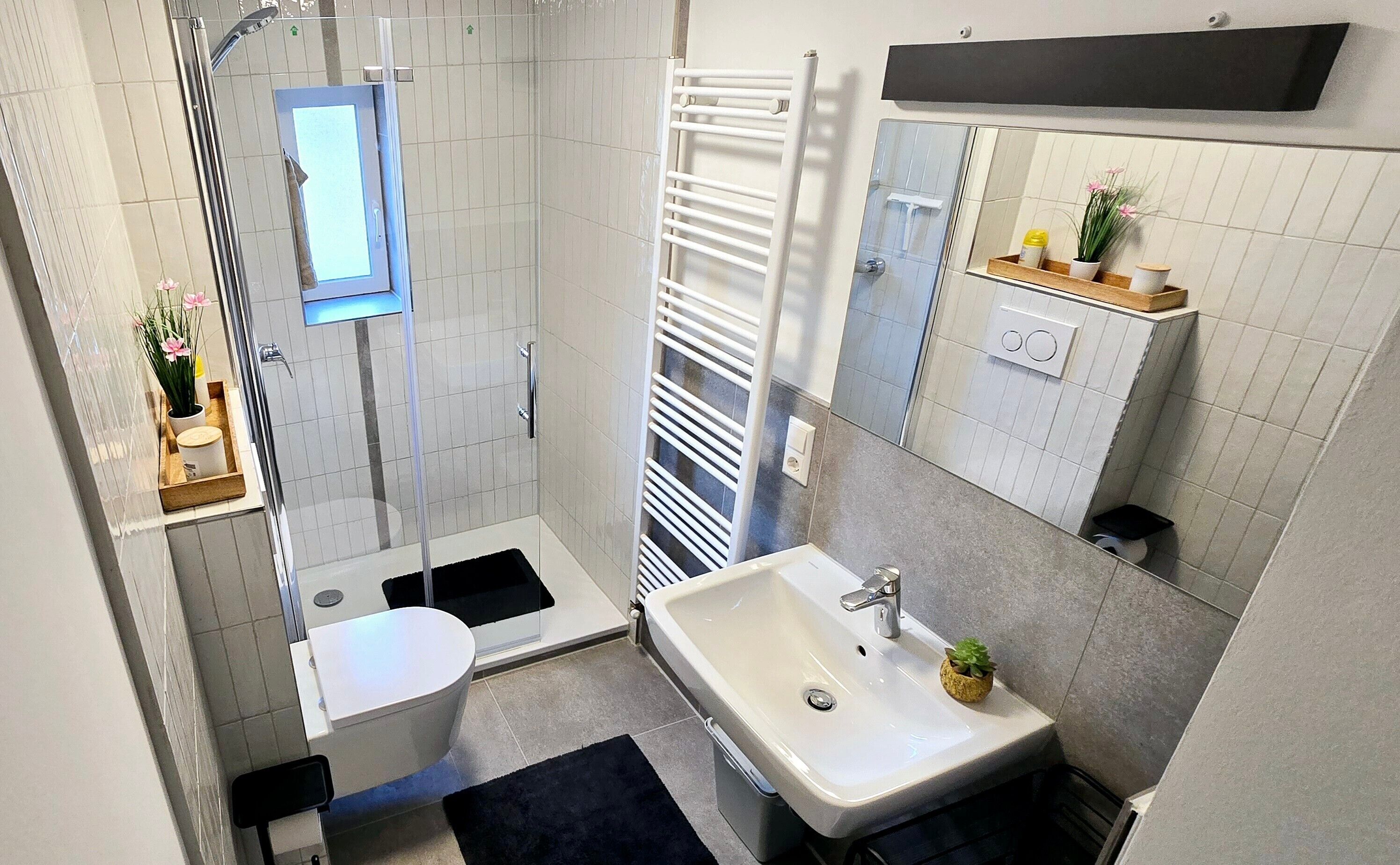 Un bagno piccolo e funzionale con doccia, toilette, lavandino e specchio sopra il lavandino.