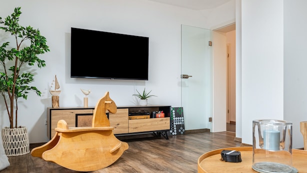 A modern living room with a wooden rocking horse, a flat-screen TV, and a wooden coffee table. - Holiday Apartment "Salem´s Treasure Manor" with Private Terrace, Shared Garden & Wi-Fi (Salem)