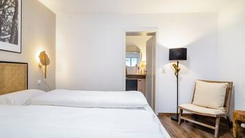 Una habitación de hotel con una cama, una silla, una lámpara y un cuadro en la pared.