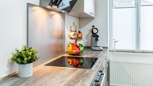 A modern kitchen with a central island, a potted plant, a coffee machine, and a window with blinds. - Holiday Apartment "Salem´s Treasure Manor" with Private Terrace, Shared Garden & Wi-Fi (Salem)