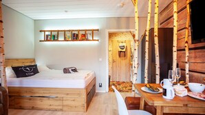 A cozy room with a wooden bed, a dining table with breakfast items, and a shelf with books.