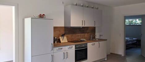 A modern kitchen with white cabinets, a wooden countertop, and a built-in oven.