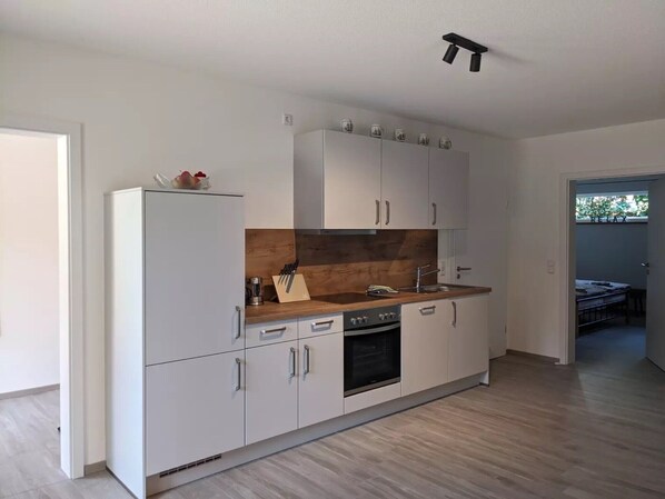 Una cocina moderna con armarios blancos, encimera de madera y horno integrado.
