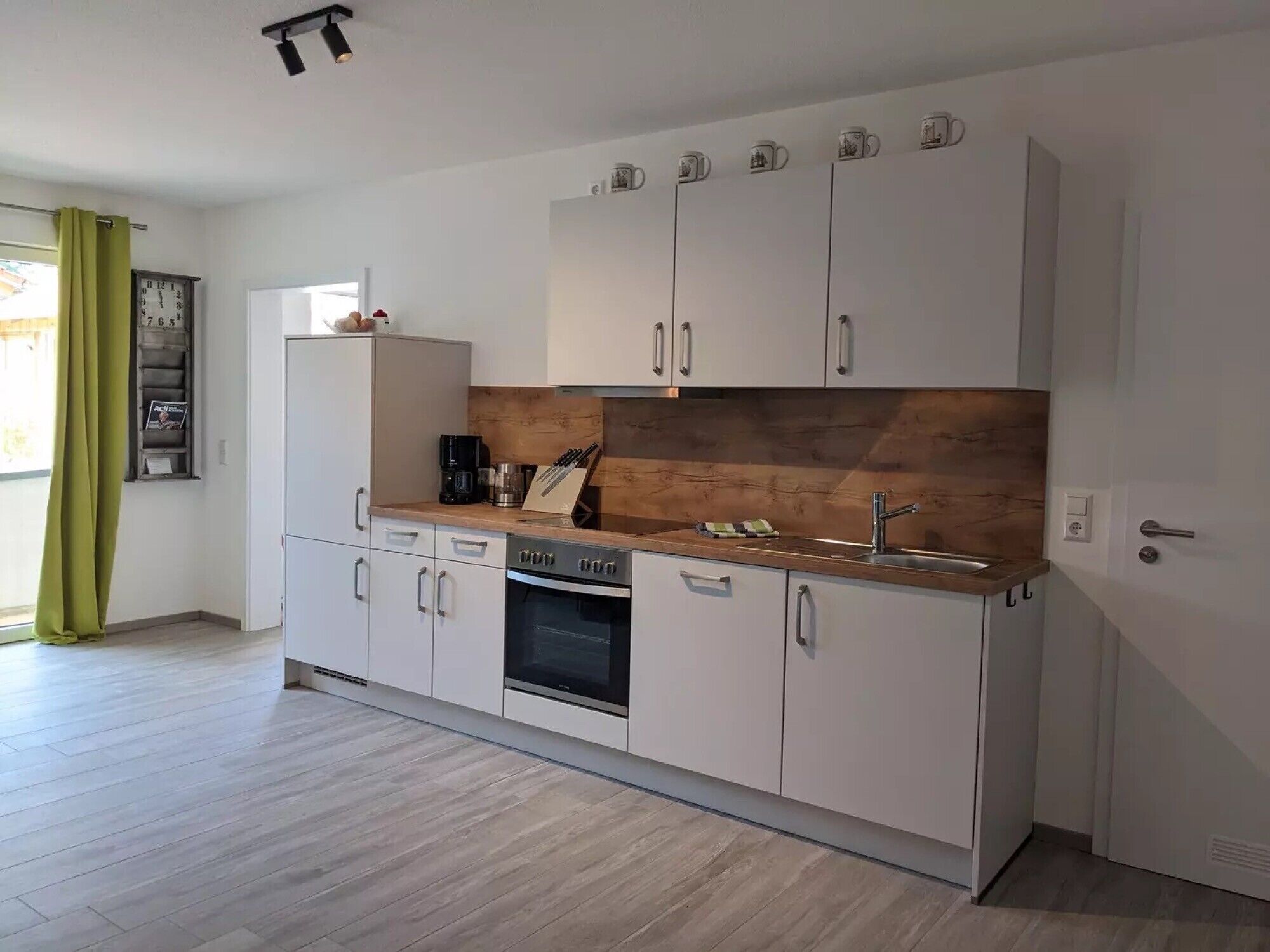 A modern kitchen with white cabinets, a wooden countertop, and a built-in oven.