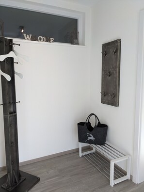 A room with a coat rack, a bench with a bag, and a wall-mounted sign.