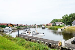 Ein Kanal mit vertäuten Booten, eine Holzsteganlage und Häuser entlang des Wassers.