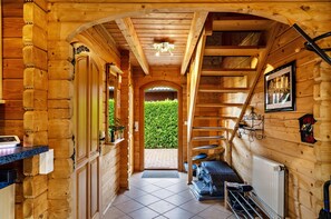 Ein Blockhauskamin mit Treppe, Heizkörper und einer Tür, die in einen Garten führt.