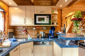 A kitchen with wooden cabinets, a microwave, a coffee maker, and a vase with flowers on the counter. - Holiday Home 'Das Alpenhaus An Der Ems' with Lake View, Private Terrace and Wi-Fi (Walchum)