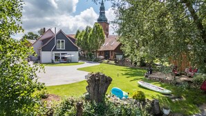 A house with a paved driveway, a lawn, and a small pond.