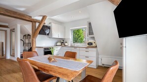 A modern kitchen with white cabinets, a wooden dining table, and a view of the outdoors.