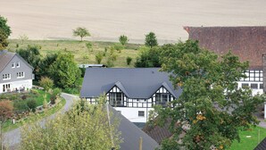 Ländliche Szenerie mit traditionellen Häusern, einer kurvenreichen Straße und einem Feld im Hintergrund.