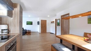 Eine moderne Küche mit Holzausbau, einem eingebauten Ofen und einem Essbereich mit Holztisch und Bank.
