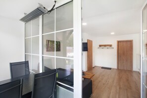 A modern office space with glass partitions, a dining area with a wooden table, and a view through a glass door. - Apartment 1, 76sqm, 2 bedrooms, max. 5 persons (Schmallenberg)