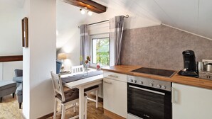Una cocina compacta con horno Bosch, encimera de madera y ventana con cortinas.