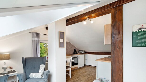 Una cocina compacta con encimera de madera, una silla blanca y una mesita.
