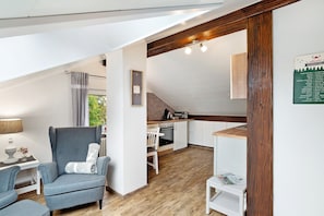 Une cuisine de taille réduite avec un plan de travail en bois, une chaise blanche et une petite table.