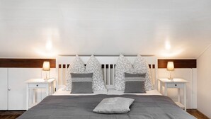 Un dormitorio con una cama, dos mesitas de noche, un cabecero y dos lámparas de pared.