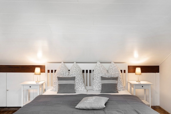 Une chambre à coucher comprenant un lit, deux tables de chevet, une tête de lit et deux lampes fixées au mur.