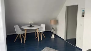 Une pièce avec une table ronde, deux chaises, une lampe et une porte.