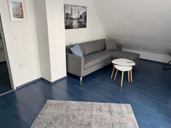 A modern living room with a grey sectional sofa, a small round table, and a grey rug.